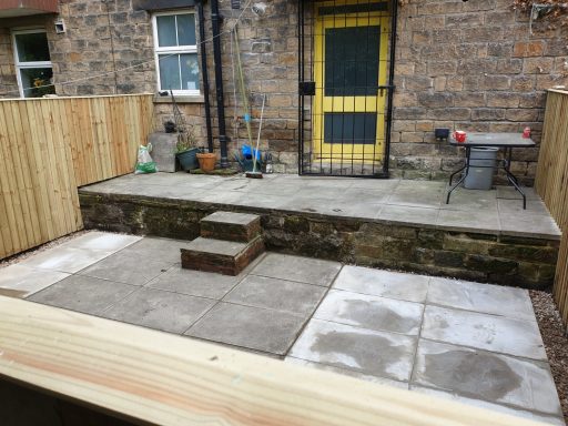 Paved outdoor area with steps and a yellow door in the background.