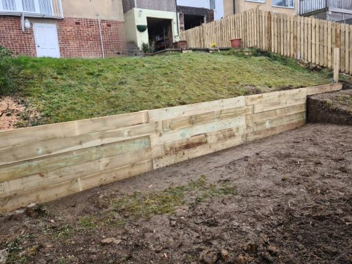 Wooden retaining wall alongside a grassy slope in a garden area.