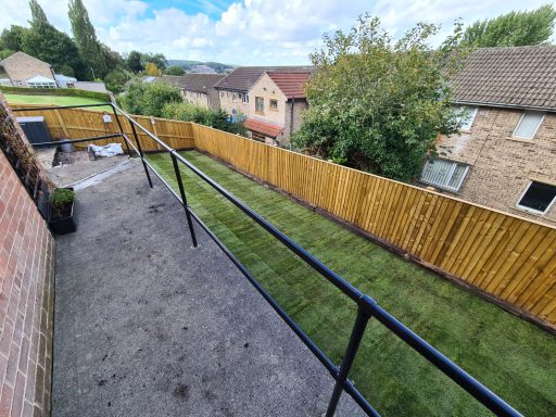 View of a garden with a wooden fence and houses in the background.