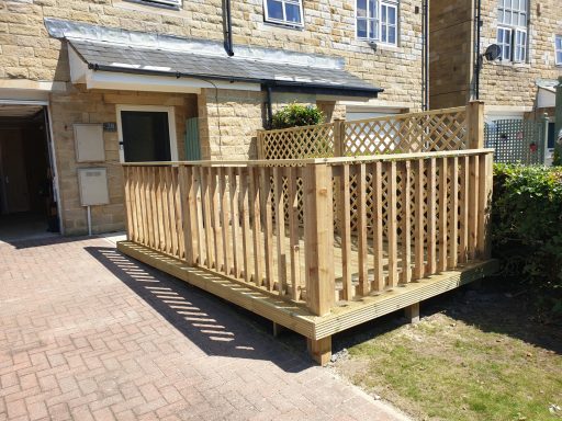 Decking with railing and privacy trellis outisde ahouse, surrounded by greenery.