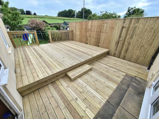 Newly built wooden decking area with a raised platform and surrounding wooden fencing.